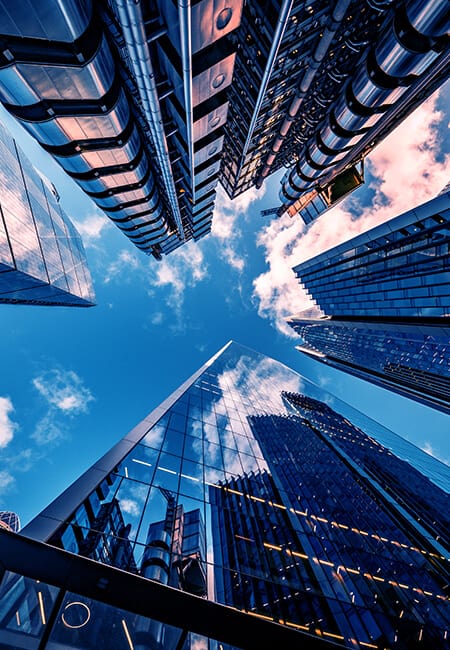 A shot looking up at skyscrapers with a bright blue sky above them.